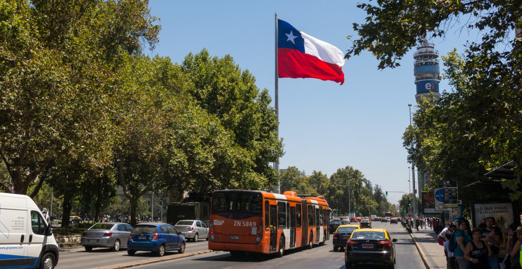 SANTIAGO DE CHILE, CHILE - JANUARY 26, 2018: Intense traffic on Avenida La Alameda, the most important street in Santiago de Chile. In the background, the flag of Citizenship Square